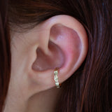 Ear wearing a beaten ear cuff in yellow gold on the upper lobe