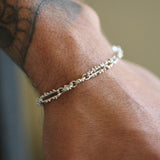 Silver bracelet on a wrist with tattoos