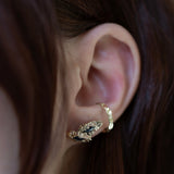 Ear wearing a gold ear cuff set with dark marquise stones