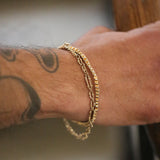 Gold bracelets on a wrist with tattoos, blurred background